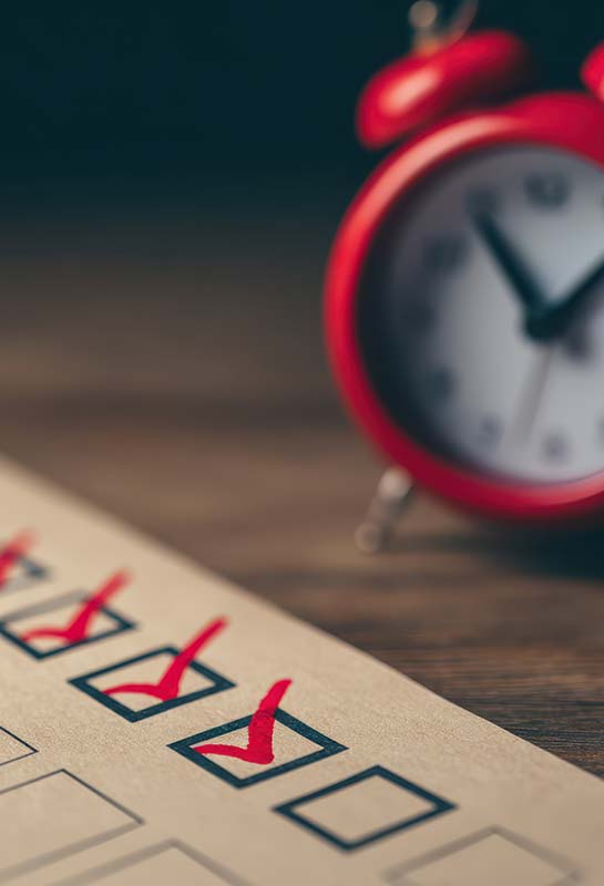Réveil rouge et checklist cochée, symbole de l’urgence de préparer la transmission d’entreprise familiale